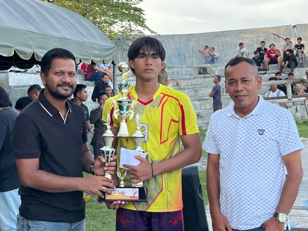 Ketua DPRK Lhokseumawe, Faisal Haji Isa, menyerahkan piala dan uang pembinaan kepada klub voli Dusun Teungoh Gampong Blang Pulo yang diterima sang kapten Umar Usman, Senin, 11 Mei 2026