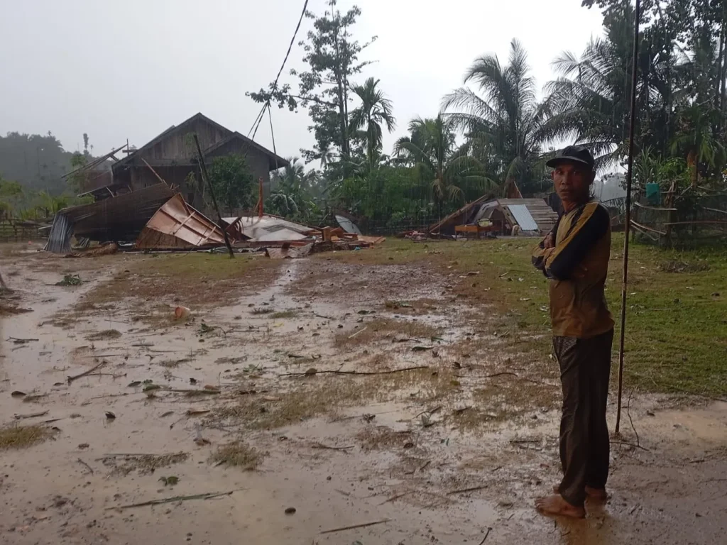 Salah Satu korban berdiri didepan rumahnya yang ambruk di terpa angin kencang